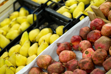 Counter with ripe pomegranates and pears in supermarket