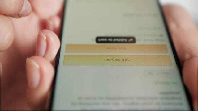 Add to cart. Female finger taps button ADD TO CART on smartphone screen. Close-up