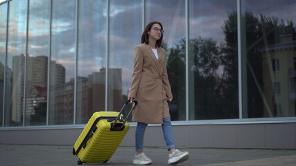 Fototapeta na wymiar A young woman walks with a yellow suitcase.