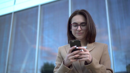 A young woman stands with a phone on the background of a business center.