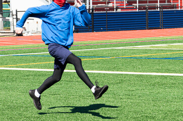 Athlete doing the sports drill straight leg bounding wearing a face gaiter mask