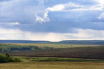 Fototapeta premium Multicolored plots of agricultural fields before rain under thunderclouds