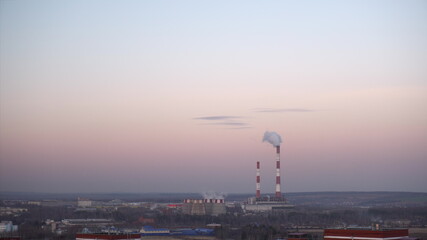 Fototapeta premium Pipes at the plant emit harmful substances into the atmosphere near the city.