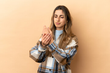 Young caucasian woman isolated on beige background suffering from pain in hands