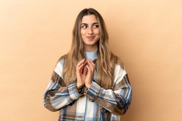 Young caucasian woman isolated on beige background scheming something