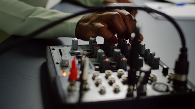 Close up of afro vlogger making sound adjustments while influencer recording social media content with pro equipment. Speaking during livestreaming, blogger discussing in podcast wearing headphones. - Powered by Adobe