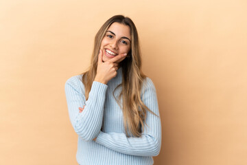 Young caucasian woman isolated on beige background happy and smiling