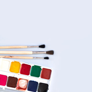 Paintbrushes with used watercolor paint palette ready to paint