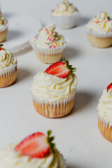 Muffins Cupcake cream decorated with colorful sprinkles on white background and strawberries 