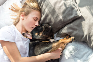 Girl sleeping with her French Bulldog dog in bed