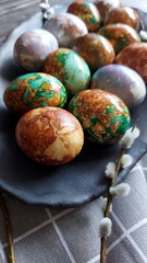 Naturally painted Easter eggs in a black clay plate on a rustic wooden background. Easter eggs painted with onion skins