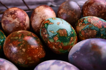 Naturally painted Easter eggs in a black clay plate on a rustic wooden background. Easter eggs painted with onion skins