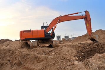 Excavator on earthworks at construction site. Backhoe on earthmoving and foundation work. Heavy machinery and equipment.