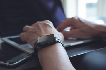 Online working from home, telework, people lifestyle concept. man wearing smartwatch working on laptop computer on table