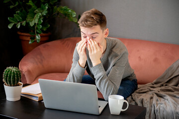 Feeling tired. Frustrated young  man looking exhausted and covering his face with hands while...