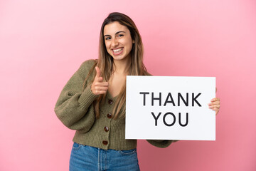 Young caucasian woman isolated on pink background holding a placard with text THANK YOU and...