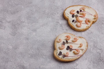 Open sandwich with shrimps and amaranth microgreens. Homemade sandwich with toaster bread on a light background, top view. Delicious shrimp sandwich with copy space