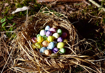 Fototapeta premium Multi-colored Easter eggs in a bird's nest. Straw and twig bird nest with egg. Easter is a Christian holiday that celebrates the belief in the resurrection of Jesus Christ