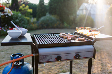 A traditional gas bbq with a selection of meats cooking in the summer sunshine