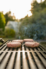 Burgers cooking over flames on grill - leisure, food and holidays concept