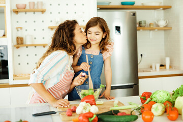 daughter mother kitchen food preparing cooking child bonding happy girl together home parent