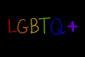 LGBTQ+ sexual concept. The shock color that represents sexual diversity is written on the blackboard. Colorful letters on a black wall.