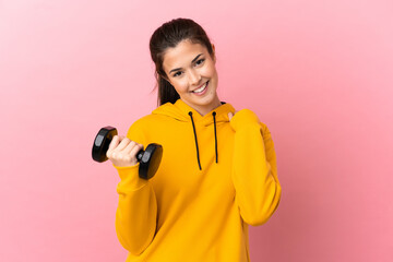 Young sport girl making weightlifting over isolated pink background laughing
