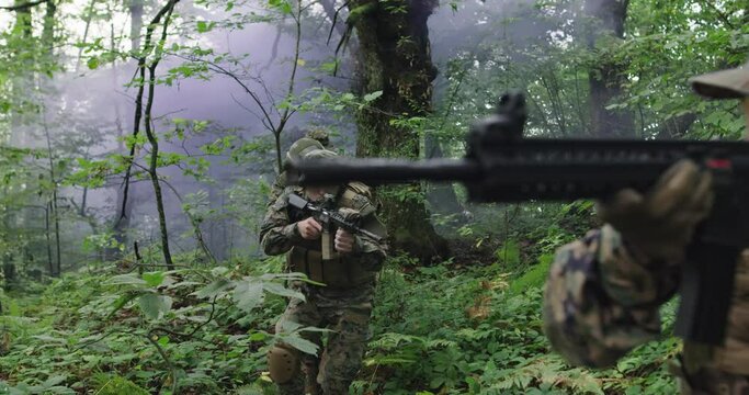 Soldiers in the smoke moving in battle operation through dense forest