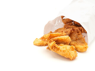Fried bananas pouring outside of a paper bag placed on white background