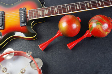 Electric guitar, tambourine and maracas on a dark background. 