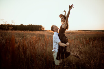 Stylish charming Caucasian young couple hugging in summer at sunset, romantic photo at sunset. Man and woman together 