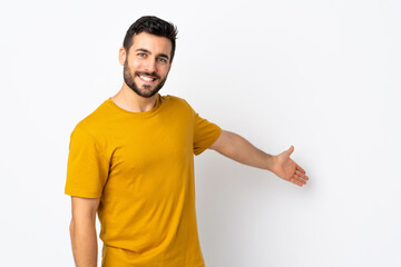 Young handsome man with beard isolated on white background extending hands to the side for inviting to come