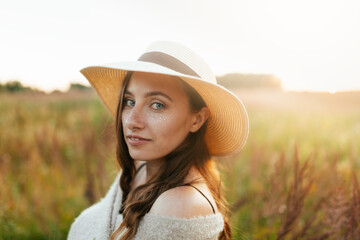 Cute caucasian young woman with long blond hair in a stylish summer hat, blurred background. Portrait of a beautiful summer girl in a brown dress, chocolate brown toning