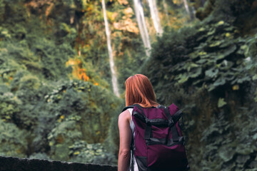 Tourist girl pose, look at waterfall in Italy (Cascata delle Marmore) in Umbria. small, calm water pressure. Evening, sunset. Summer, bottom view. Backpack. Copy space