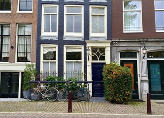 Fototapeta na wymiar Authentic houses by the channel in Amsterdam, Netherlands. Early autumn. Bicycles. Famous dutch architecture 