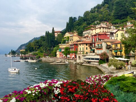 Varenna, Italy. Spectacular view from lakeside cafe. Colourful village by the Como lake, geranium, mountain, park, boat. Horizontal