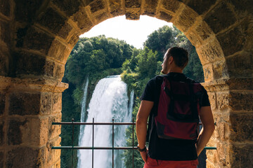 Tourist man look at waterfall in Italy (Cascata delle Marmore) in Umbria. Large water pressure,...