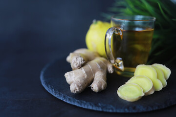 Ginger root whole and sliced. Ginger tea with lemon on the dark background. Fresh ginger root on...
