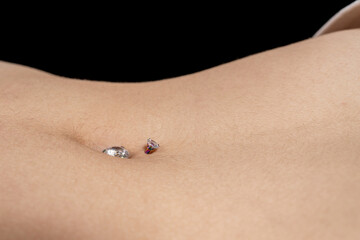 Belly button or navel piercing of sexy young woman isolated on black background. Horizontal shot.