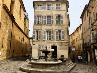Fototapeta na wymiar AIX-EN-PROVENCE, FRANCE. Fountain, cobblestone, summertime, traditional architecture. Date of photo is 10.06.2019. Unrecognizable people. Road sign