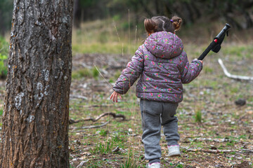Little girl hiking in the woods on a cold autumn day with coat. Active family holidays with children. Outdoor fun and healthy activity