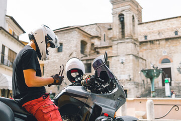 Fototapeta na wymiar Handsome man in white helmet sitting on old adventure motorbike. Travel and vacation concept. Freedom. Narni, Italy