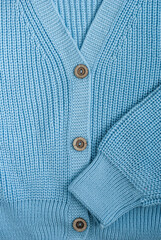 Female light blue knitted acrylic cardigan closeup with three brown buttons