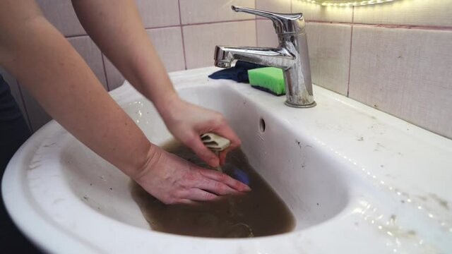 The woman uses a plunger to clean the blockage in the sink.