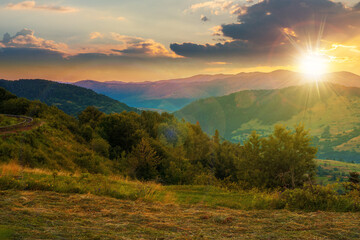 Fototapeta na wymiar mountainous rural landscape at sunset. grassy meadow on top of a hill. clouds above the ridge in evening light. view in to the distant valley