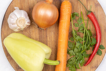 Top view of fresh vegetables on the round wooden cutting board