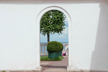 View of the topiary and the sea through the doorway in the white wall. Hidden park. Secret garden.