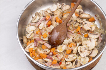 Cooking mushrooms with onions carrots and bacon