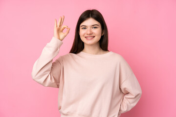 Young Ukrainian teenager girl over isolated pink background surprised and showing ok sign