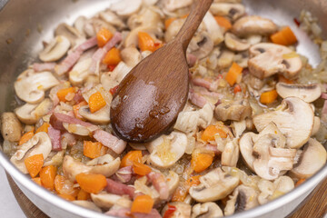 Cooking mushrooms with onions carrots and bacon